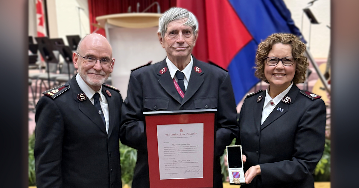A man holds a certificate, standing between a man and a woman
